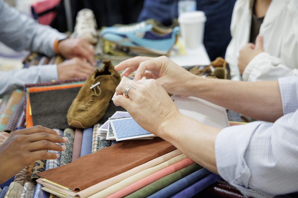 Hands sorting leather samples on a booth table.