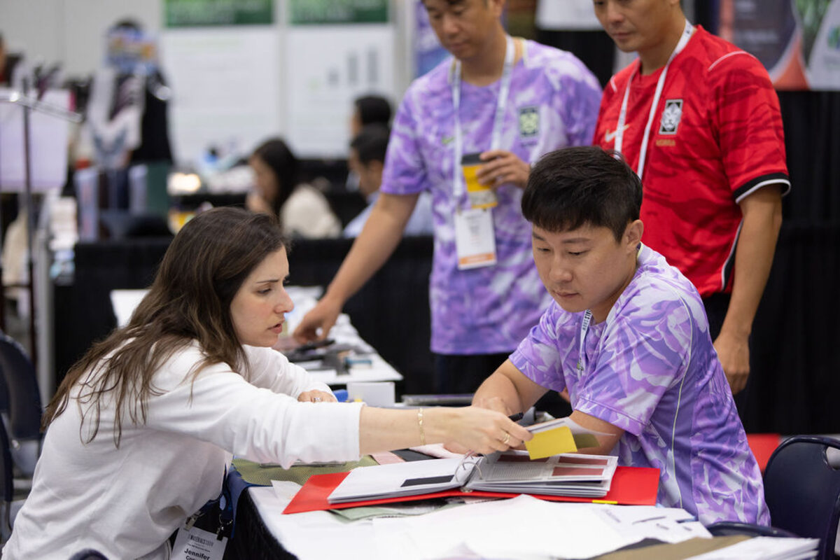 Visitors and an exhibitor reviewing samples together.